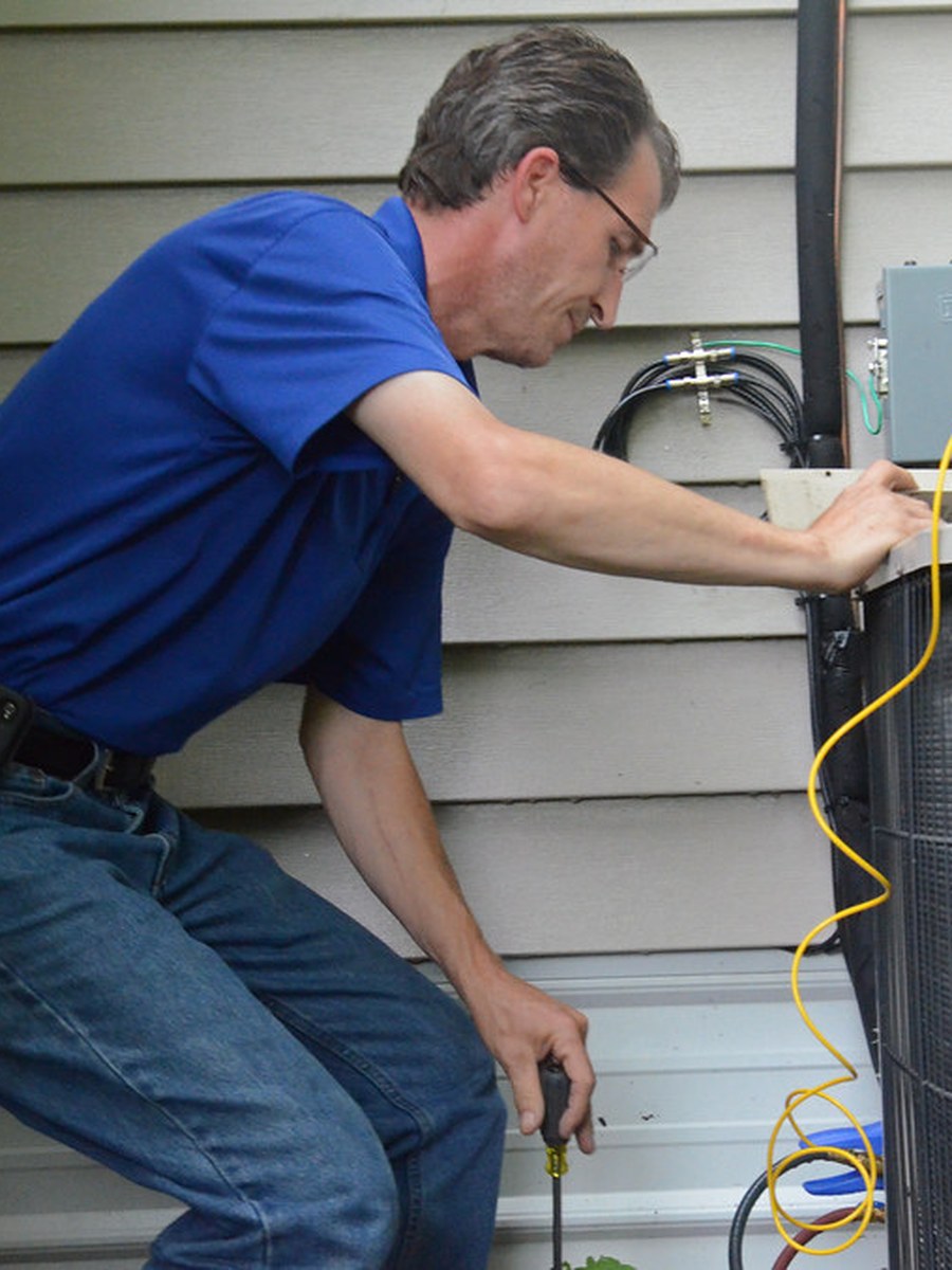 Technician working on a residential air conditioning condenser